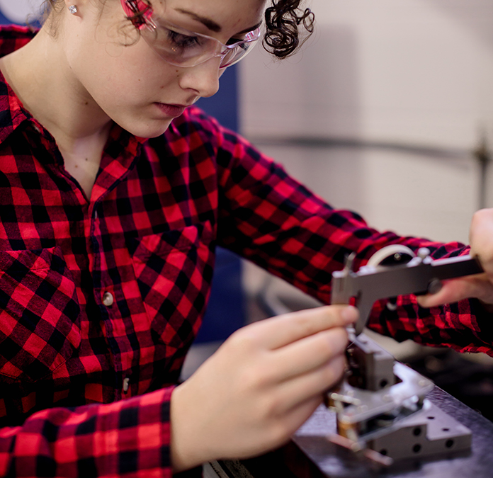 female student making a precise measurement on tool bench
